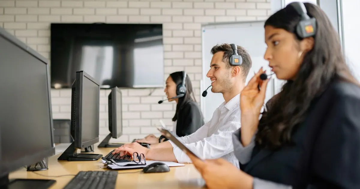 Equipe de atendimento usando headsets e computadores em um escritório